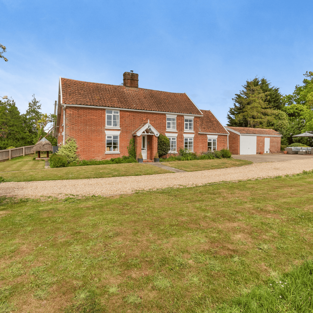 Red brick Suffolk farmhouse behind a lawn and gravel drive